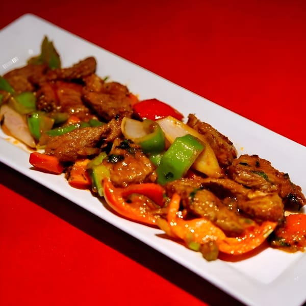 Everest Restaurant's Indian dish with meat, red and green bell peppers, and onions on a white plate.